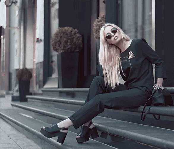 Web Developer wearing shades, sitting on steps of an office building alongside her purse.